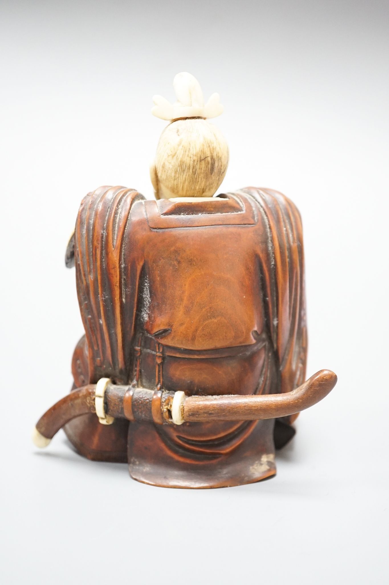 A Japanese wood and ivory okimono of a kneeling samurai holding a baby, Meiji period, unsigned, 12cm